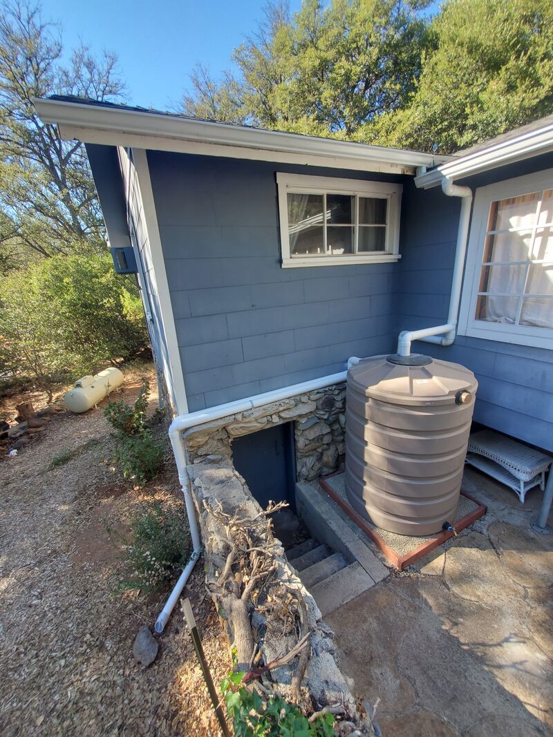 420 gallon rainwater harvesting tank connected to house gutters with overflow to ground in Julian, CA