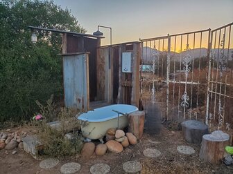 Outdoor shower and bathing tub system built using reclaimed and local materials like wood and corugaed metal sends greywater to plants nearby in Ramona, San Diego County, Calofornia