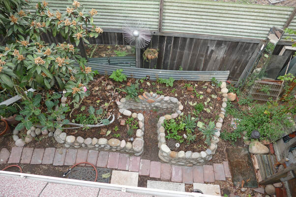 Aerial view keyhole raised garden bed made of round local rocks and earthen mortar in Normal Heights, San Diego
